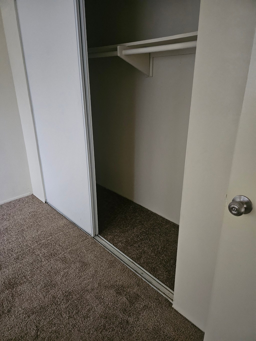 a closet with a mirrored door and a carpeted floor