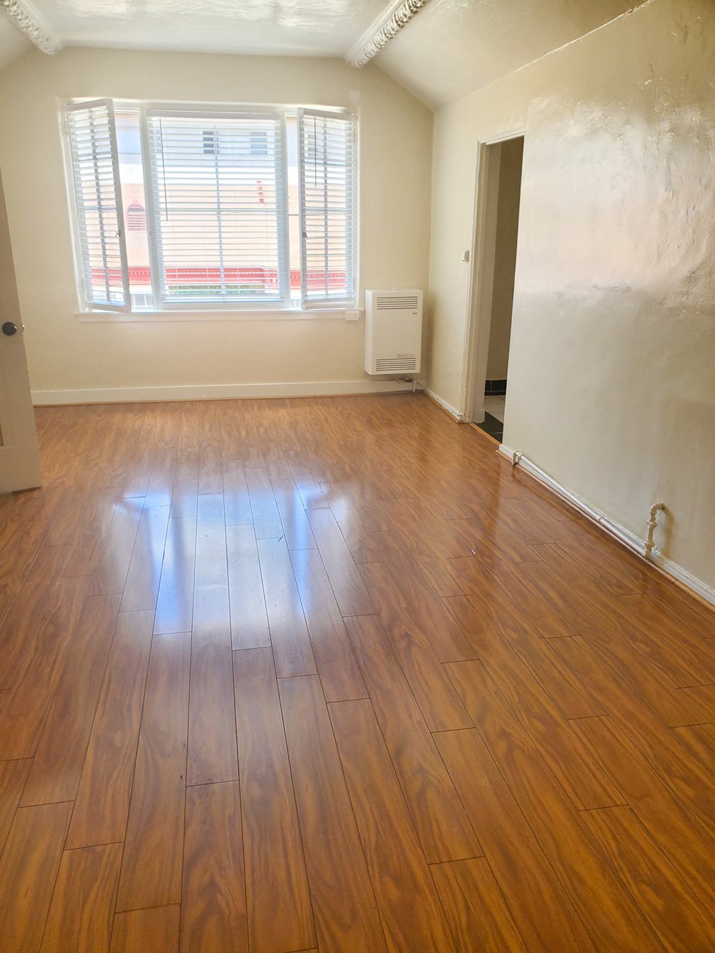 an empty living room with wooden floors and a window