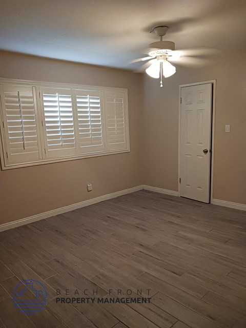 the living room of a home with a wooden floor and a ceiling fan