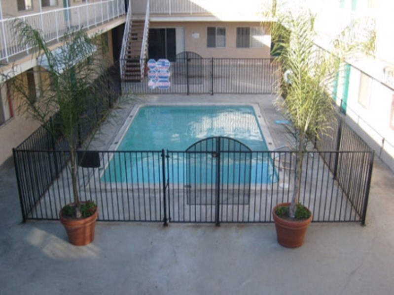 a swimming pool in front of a house behind a fence