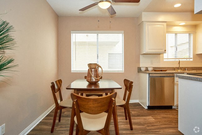 a dining area with a table and chairs and a kitchen in the background