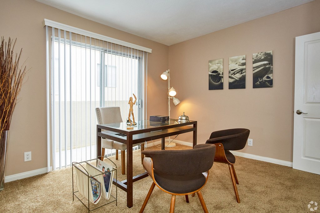 a desk and chairs in a living room with a large window