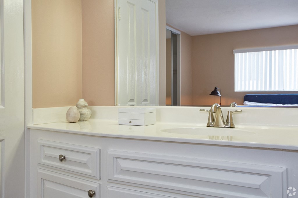 a bathroom with white cabinets and a large mirror