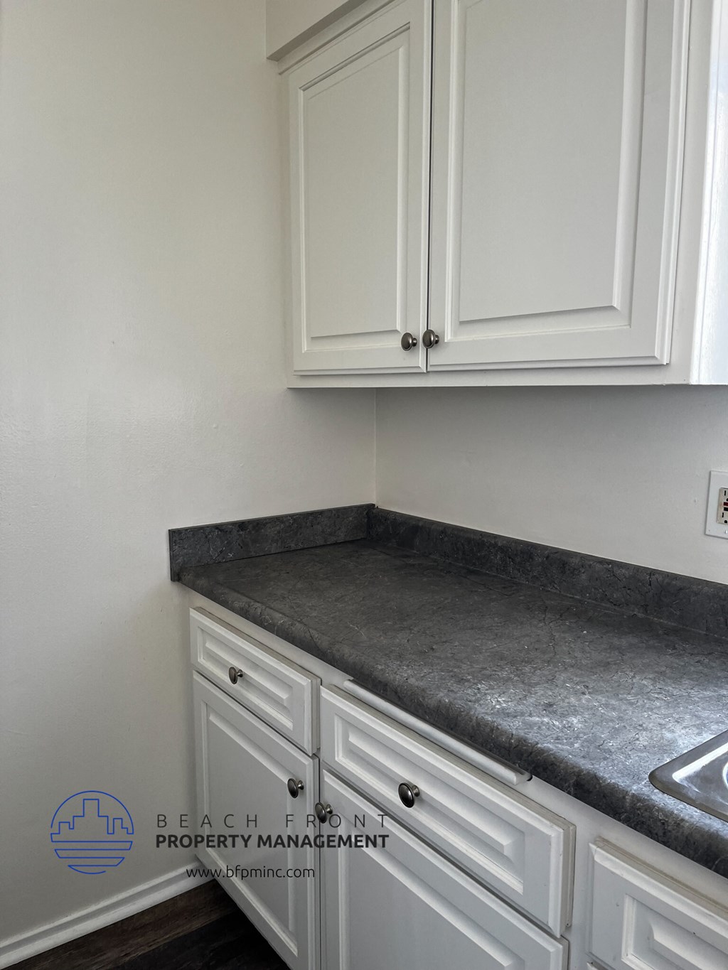 a kitchen with white cabinets and gray countertops
