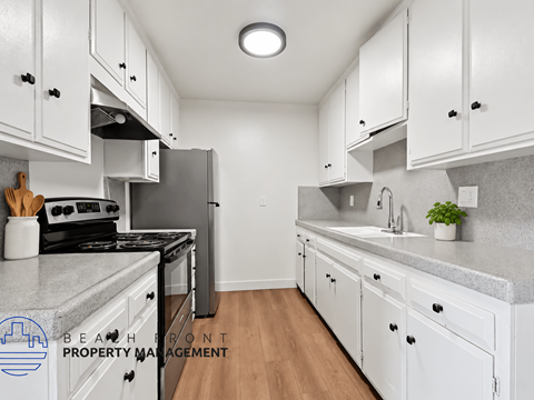 A kitchen with white cabinets and a Beafront Property Management logo.