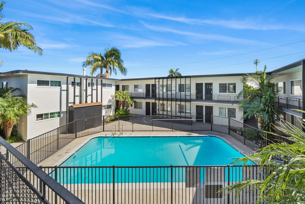 a swimming pool in front of a building with palm trees