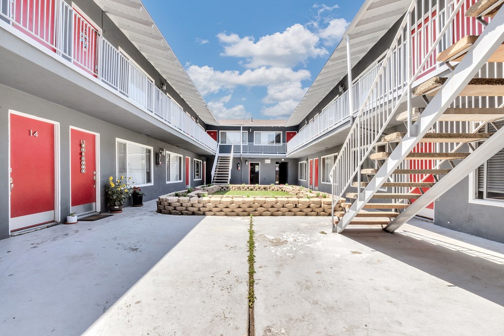 a courtyard with a flower bed in the middle between two apartment buildings