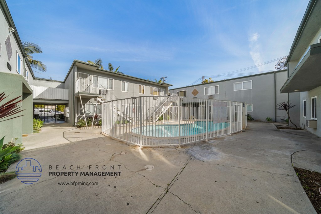 a fenced in swimming pool in the middle of two buildings