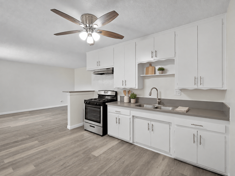 A kitchen with white cabinets and a wood floor.