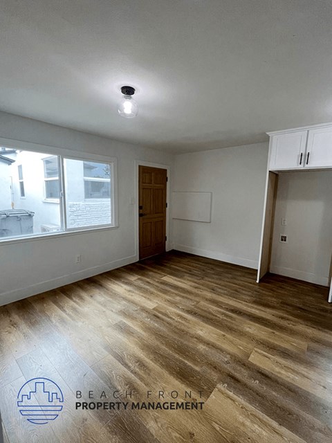 an empty living room with wood flooring and a window