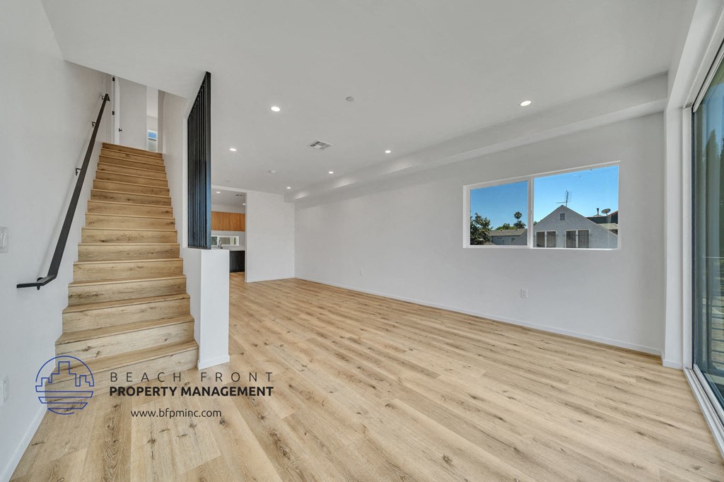 a renovated living room with a staircase and wood flooring