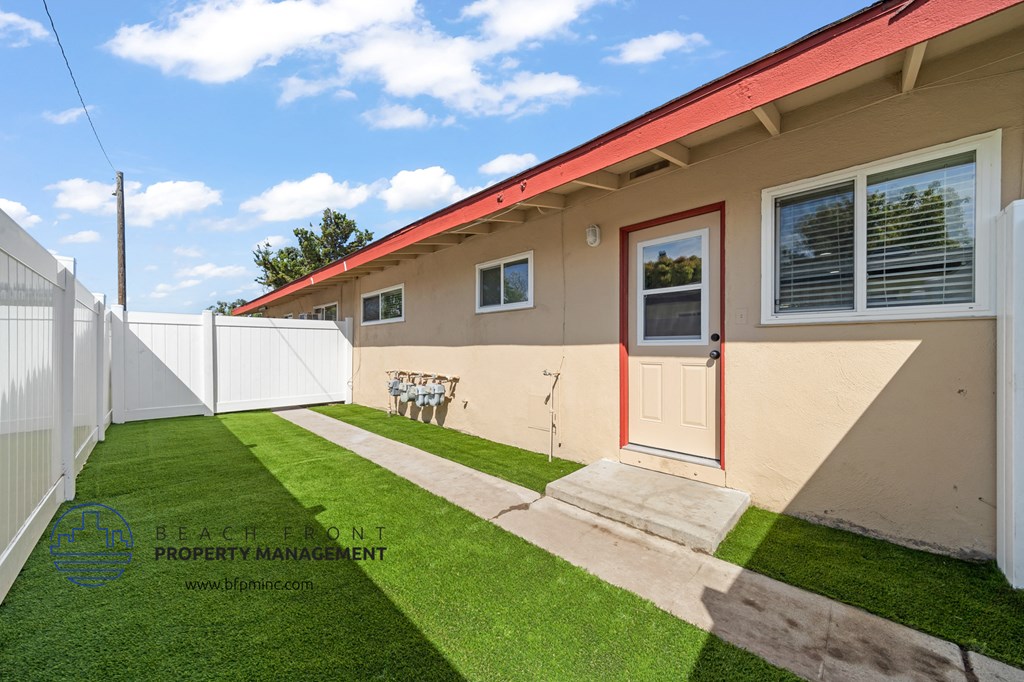 a backyard with a lawn and a white fence