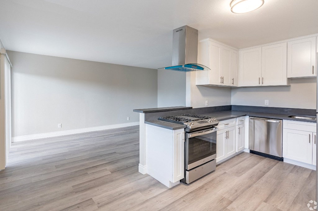 an empty kitchen with white cabinets and stainless steel appliances