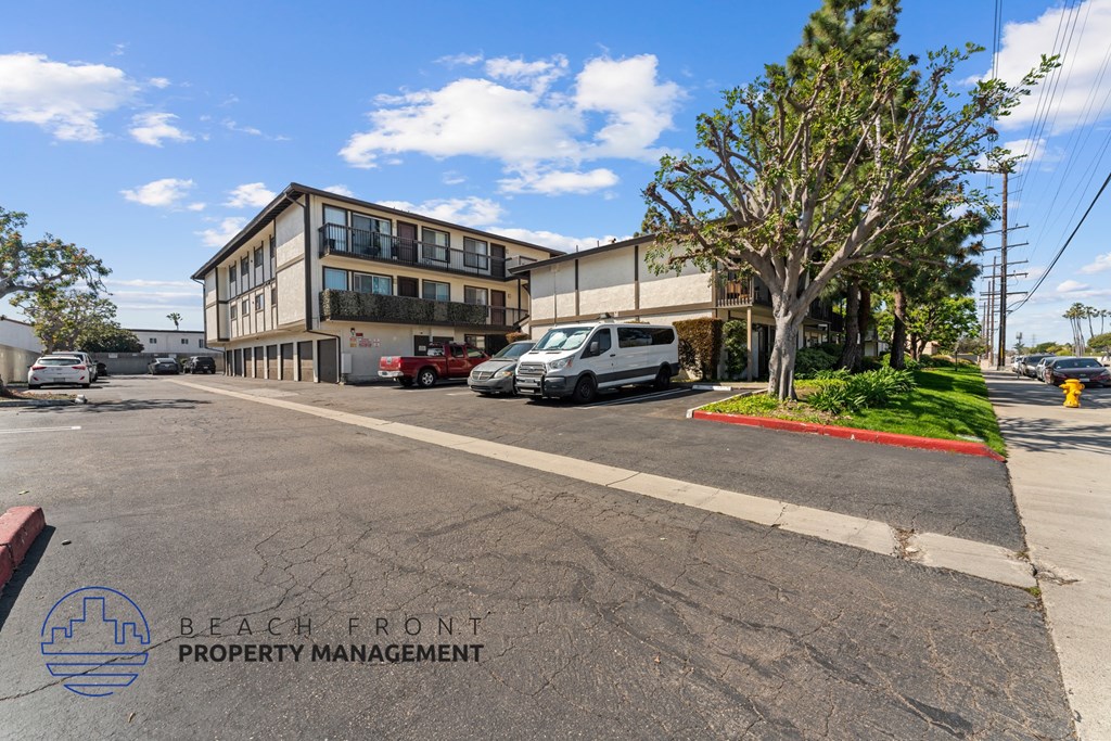 A parking lot with a building and a tree in the background.