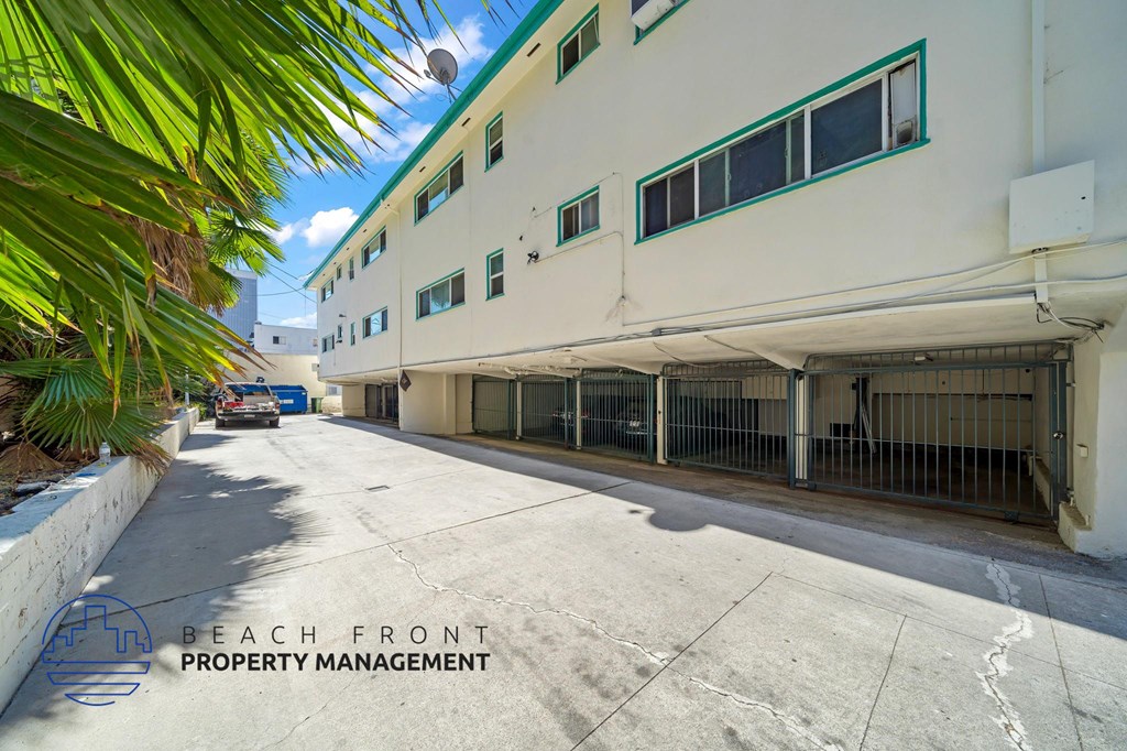 A white building with green trim and a sign that says "Beach Front Property Management".