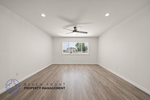 A spacious room with a ceiling fan and wooden flooring.