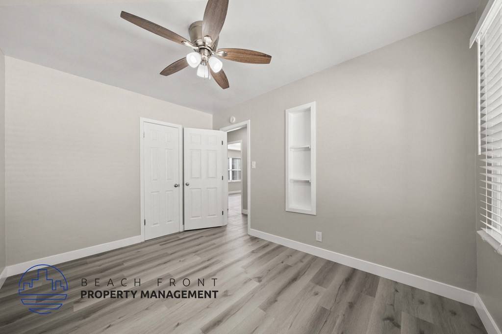 A room with a ceiling fan and a logo for Beach Front Property Management.