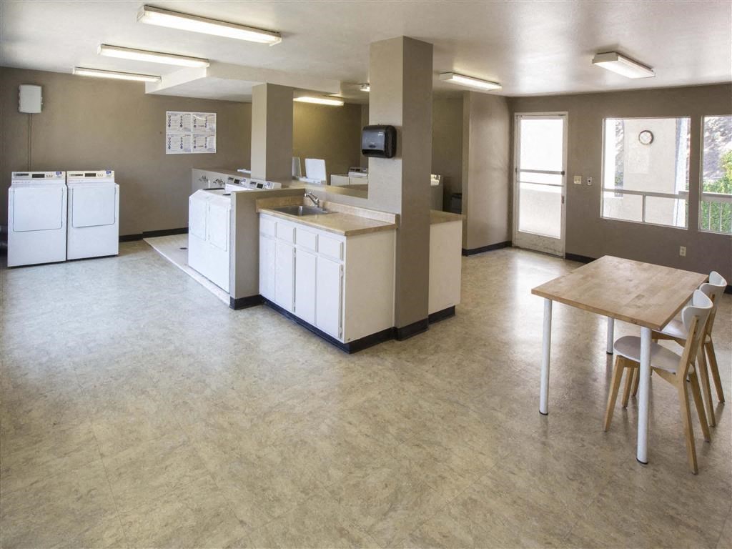 an empty kitchen and dining room with white appliances and a table