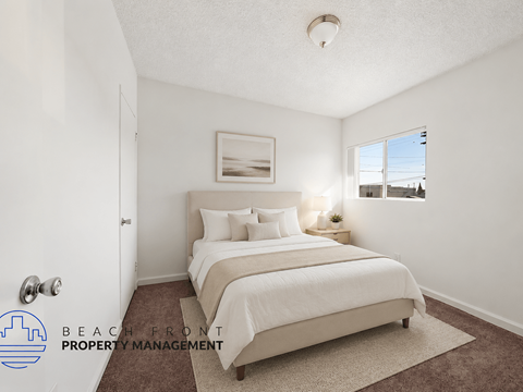 A bedroom with a large bed and a window overlooking the beach.