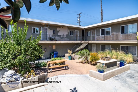 A sunny day at the beachfront property with a picnic table and plants.