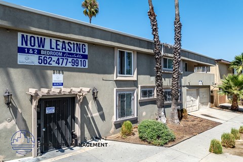 A building with a sign that says "NOW LEASING" and a phone number.