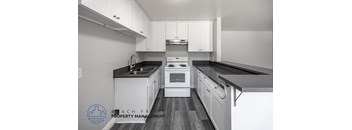 A kitchen with white cabinets and black countertops.