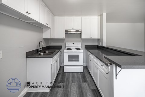 A kitchen with white cabinets and black countertops.