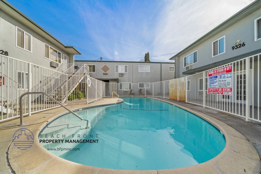 a pool with a fence around it in front of apartments