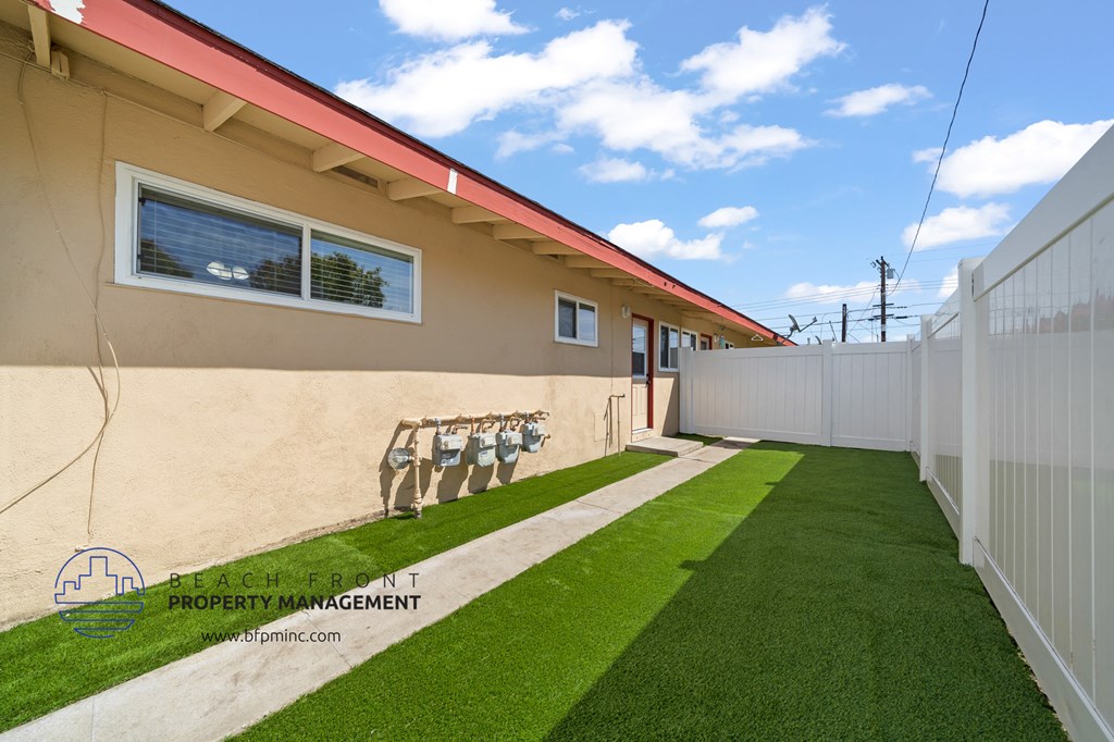 a backyard with a grassy area and a white fence