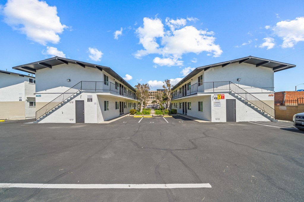 an empty parking lot in front of two buildings with stairs