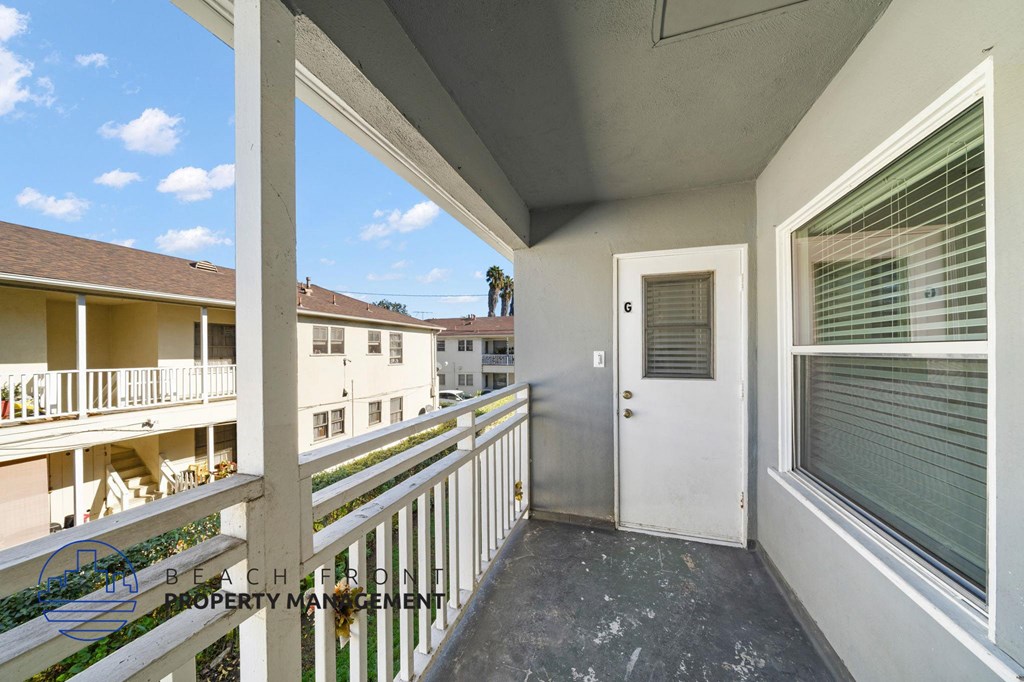 A balcony with a white door and window with blinds.