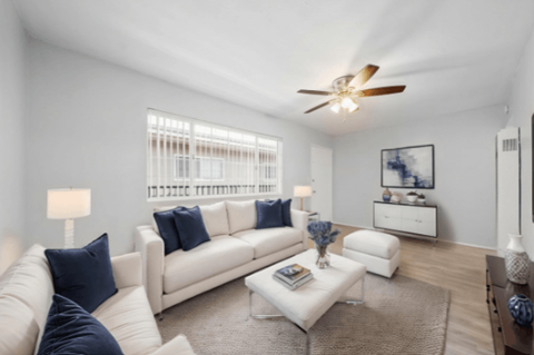 A living room with a white couch, a coffee table, and a ceiling fan.