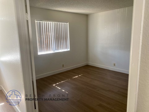A room with wooden flooring and a window with blinds.