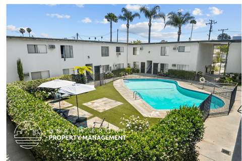 an aerial view of a pool in front of a white building with palm trees