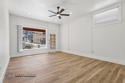 A spacious room with wooden flooring and a ceiling fan.