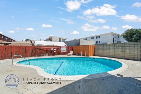 A pool surrounded by a fence with the words Beach Front Property Management on it.