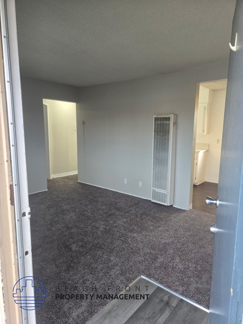 A room with a carpeted floor and a door on the right side.