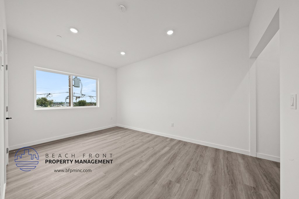 a living room with white walls and wood flooring and a window