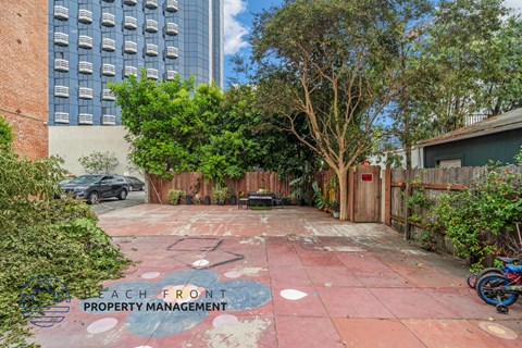 a backyard with a red brick driveway and a fence and trees