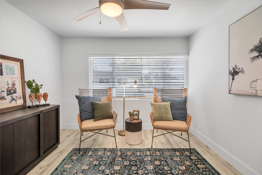 A room with two chairs and a table with a plant on it.