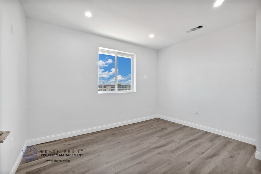 a room with white walls and wood floors and a window