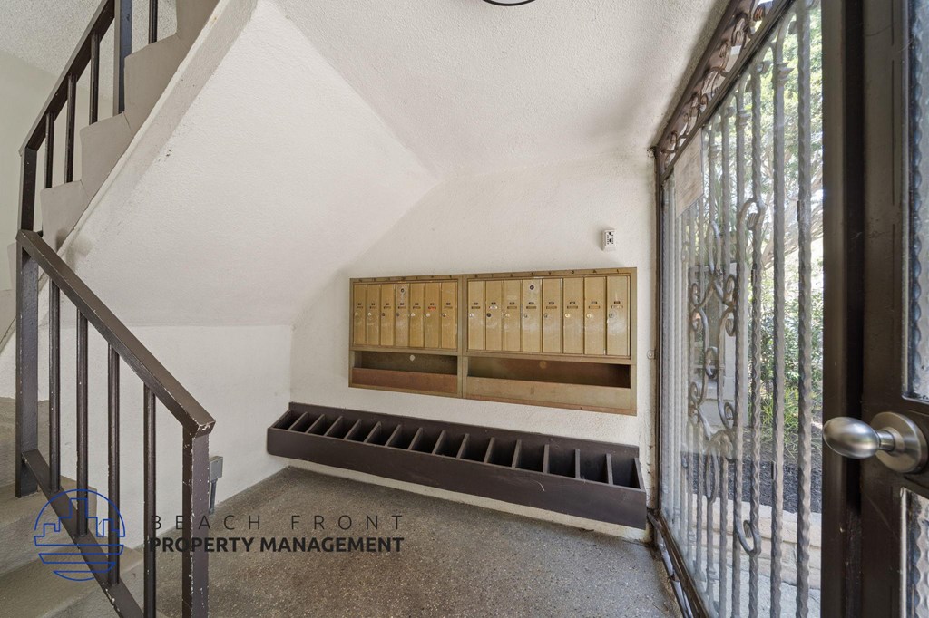 A staircase with a wooden handrail and a metal balustrade leads to a landing with a window and a vent.