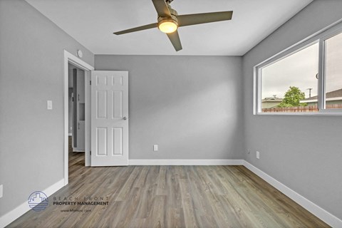 an empty bedroom with a ceiling fan and a window