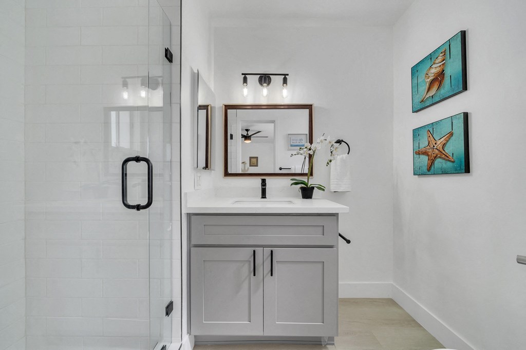 a white bathroom with a sink and a shower