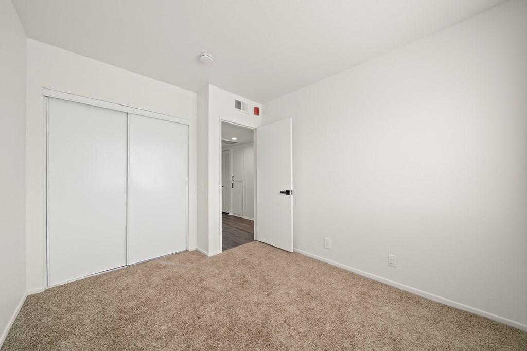 a bedroom with white walls and carpeting and white doors