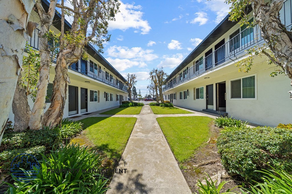 a courtyard between two units of a building with grass and trees