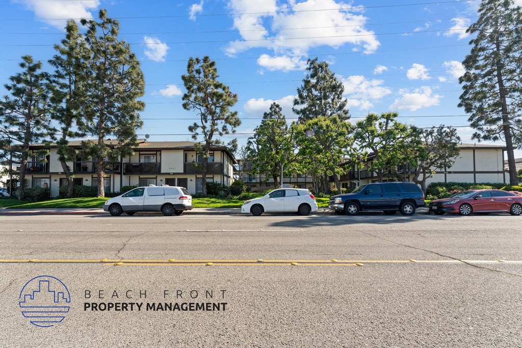 A parking lot with cars and a building in the background with the words Beach Front Property Management.