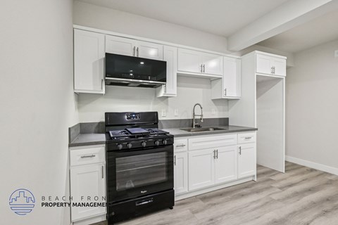 A kitchen with white cabinets and a black stove top oven.