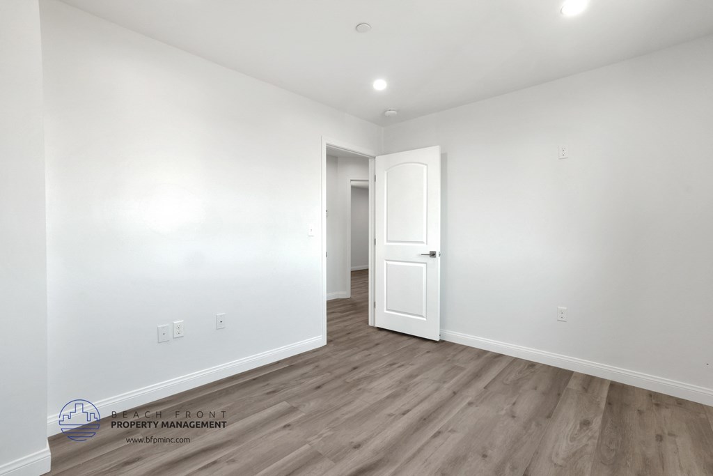 a bedroom with white walls and wood flooring and a white door