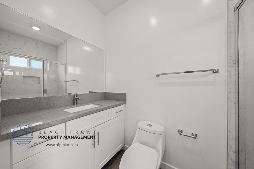 a white bathroom with a toilet and a sink and a mirror